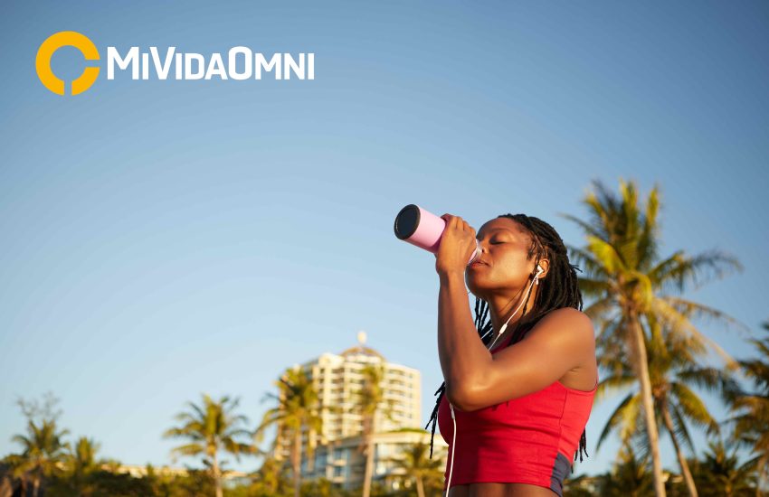 Hermosa joven deportista bebiendo agua con vitaminas después de trabajar al aire libre